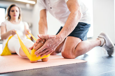 Unrecognizable senior physiotherapist working with a female patient.